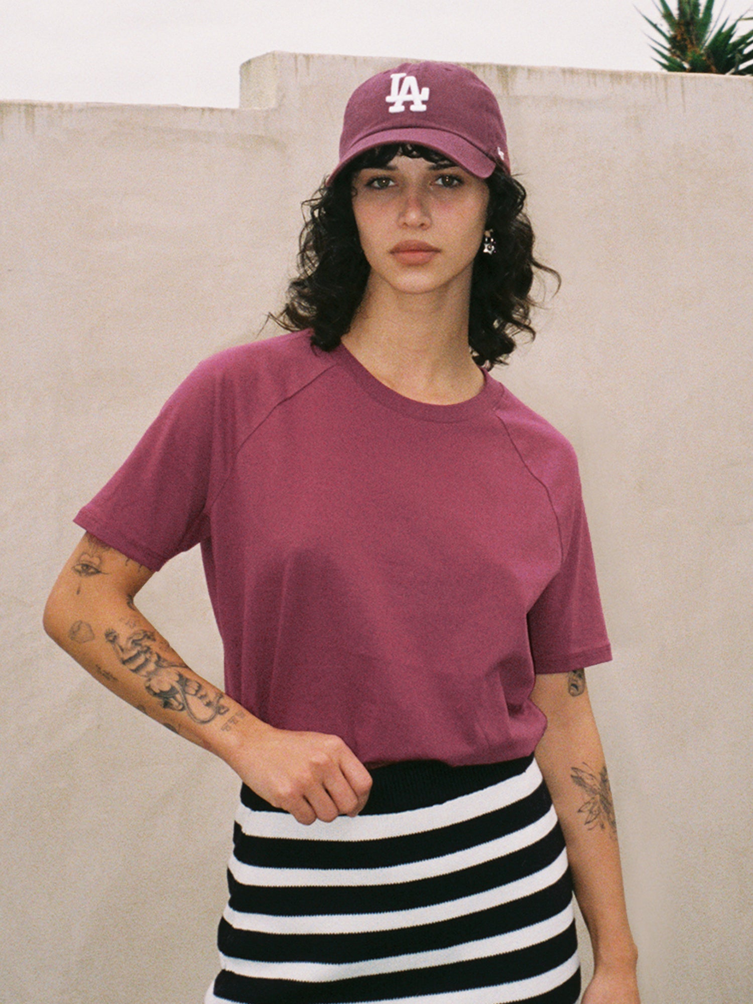 Female model in dark red raglan t-shirt and LA baseball cap