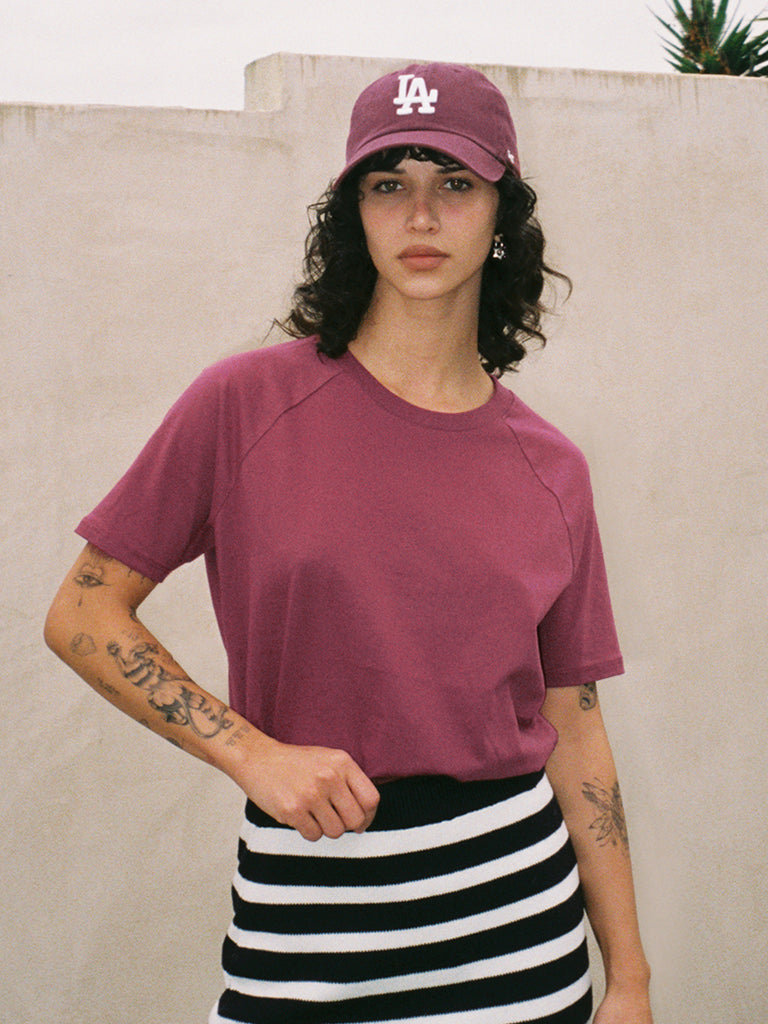 Female model in dark red raglan t-shirt and LA baseball cap 